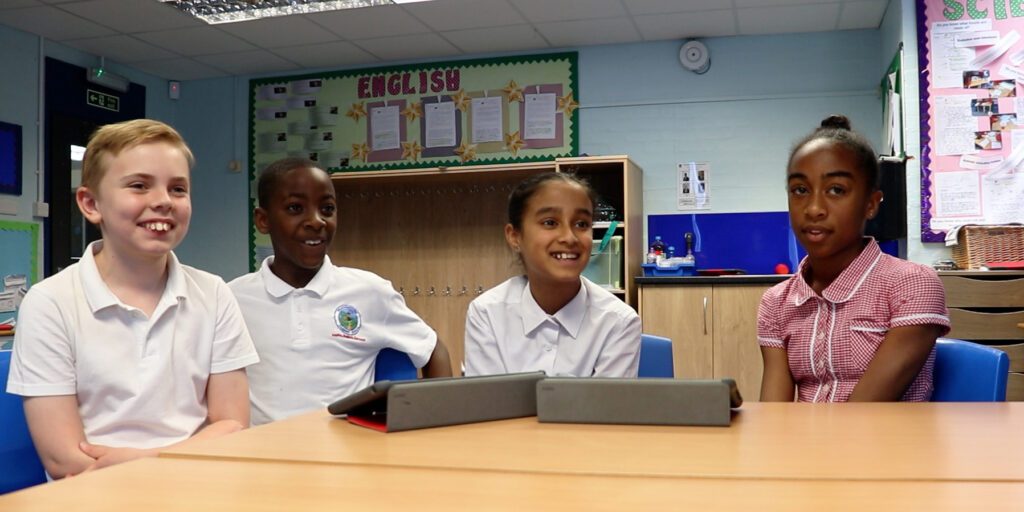 4 pupils sat at a desk with iPads